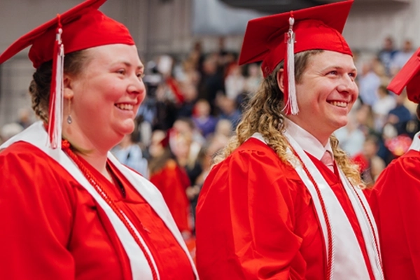 Two graduating students with red honors cords