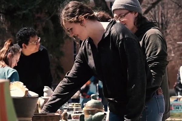 Students looking at pottery for sale on the campus mall