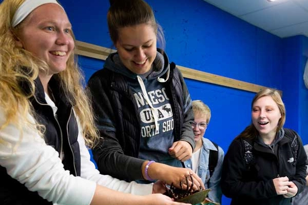 Oceanarium lab assistant holding horseshoe crab and other students looking at it