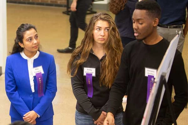 Three students presenting their poster at the Student Academic Conference